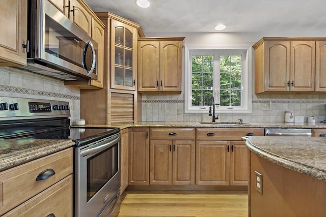22 Mikayla Ann Dr, Rehoboth, MA 02769 - kitchen with appliances with stainless steel finishes, a sink, light stone counters, light wood finished floors, and backsplash