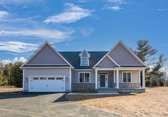 craftsman-style house with aphalt driveway, stone siding, a porch, and an attached garage