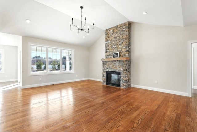 unfurnished living room featuring a notable chandelier, plenty of natural light, lofted ceiling, and wood finished floors