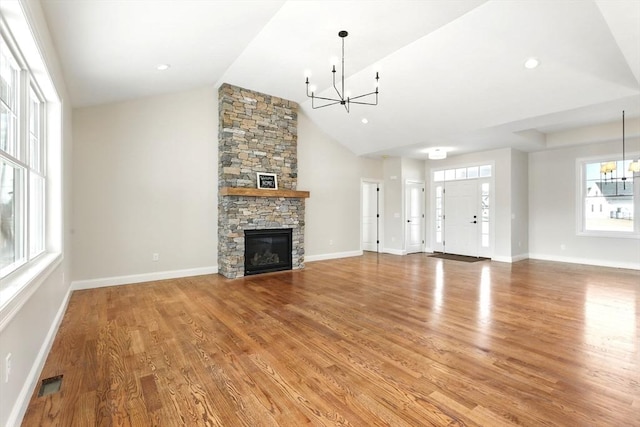 unfurnished living room featuring a stone fireplace, an inviting chandelier, and light wood finished floors