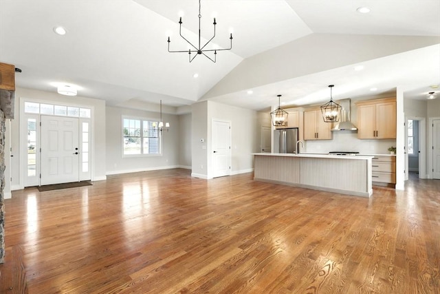 unfurnished living room featuring light wood finished floors, baseboards, recessed lighting, an inviting chandelier, and high vaulted ceiling