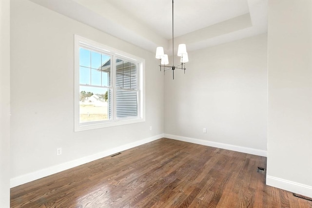 unfurnished room featuring baseboards, a notable chandelier, a raised ceiling, and dark wood-style flooring