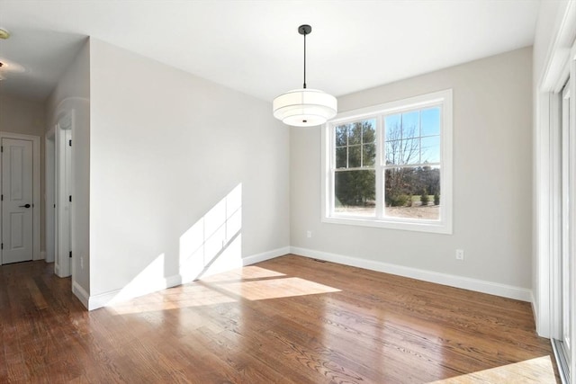 unfurnished dining area with baseboards and wood finished floors