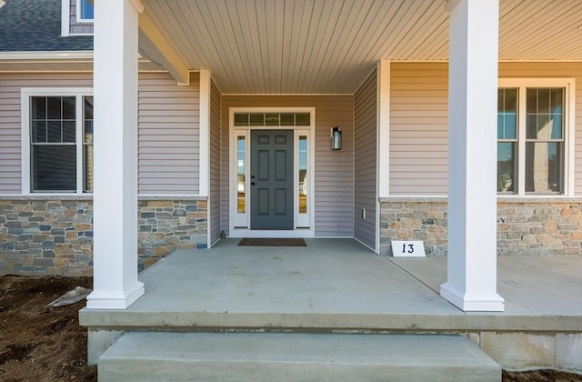 property entrance featuring stone siding and covered porch