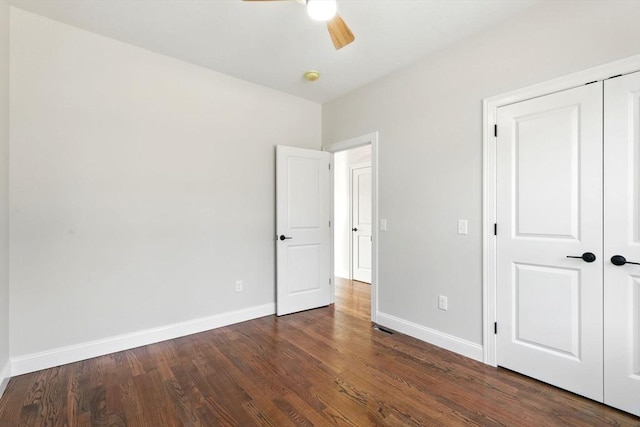 unfurnished bedroom featuring a closet, ceiling fan, baseboards, and dark wood-style flooring