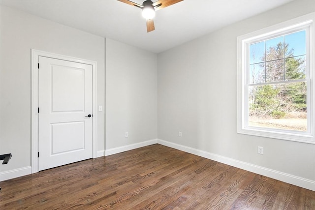 spare room with baseboards, ceiling fan, and dark wood finished floors