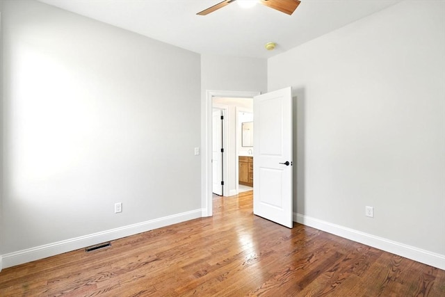 empty room featuring baseboards, wood finished floors, visible vents, and ceiling fan