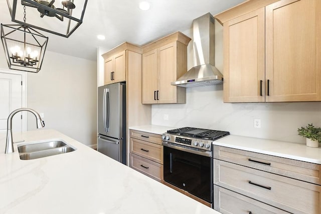 kitchen featuring light brown cabinets, a sink, appliances with stainless steel finishes, wall chimney range hood, and a chandelier