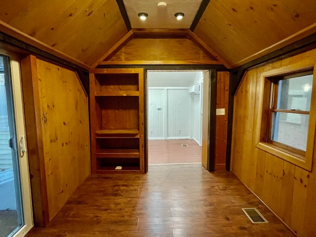 interior space featuring lofted ceiling, built in shelves, wooden ceiling, and wood walls