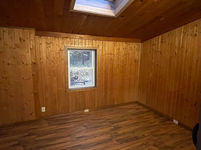 empty room featuring wooden walls, hardwood / wood-style floors, wood ceiling, and a skylight