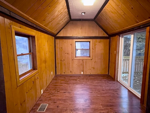 additional living space with lofted ceiling, hardwood / wood-style flooring, a wealth of natural light, and wooden walls