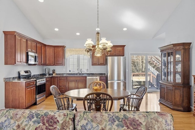 kitchen featuring hanging light fixtures, light wood-style flooring, a notable chandelier, and appliances with stainless steel finishes