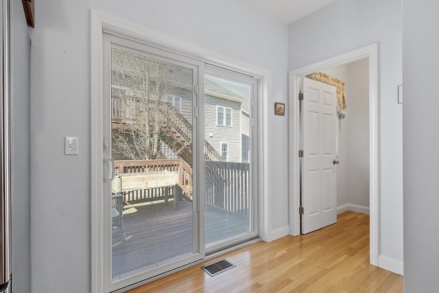 doorway featuring light wood-style floors, visible vents, and baseboards