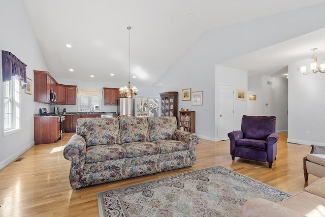 living room featuring baseboards, a notable chandelier, high vaulted ceiling, and light wood finished floors