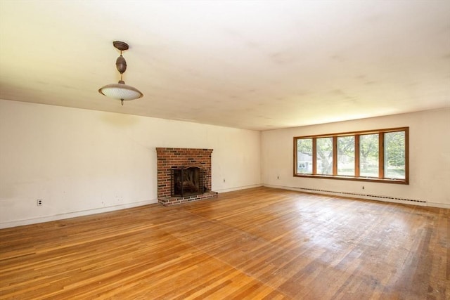 unfurnished living room featuring baseboard heating, light wood finished floors, a brick fireplace, and baseboards