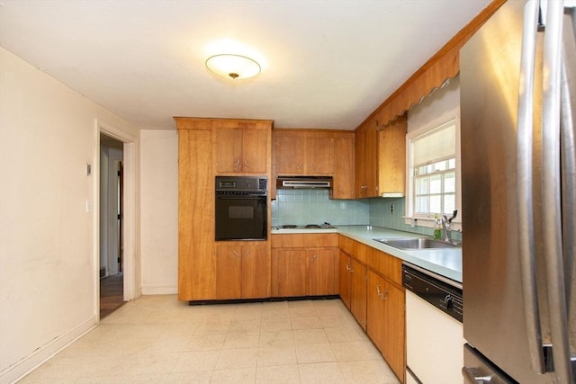 kitchen with appliances with stainless steel finishes, a sink, light countertops, backsplash, and under cabinet range hood
