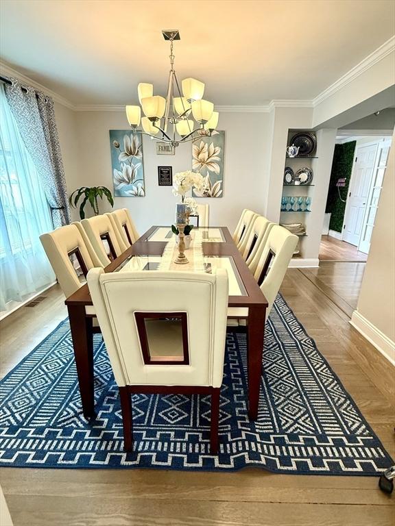 21 Florence Ave, Lowell, MA 01851 - dining room featuring a chandelier, crown molding, baseboards, built in shelves, and wood finished floors