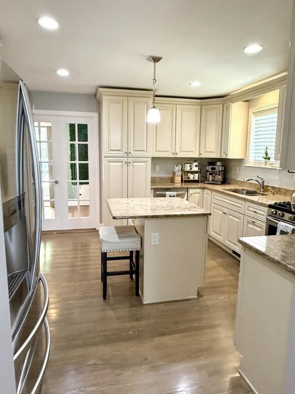 21 Florence Ave, Lowell, MA 01851 - kitchen with stainless steel appliances, a center island, decorative light fixtures, light stone counters, and a sink