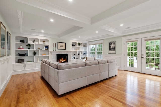 living room featuring a healthy amount of sunlight, light hardwood / wood-style floors, beam ceiling, and ornamental molding