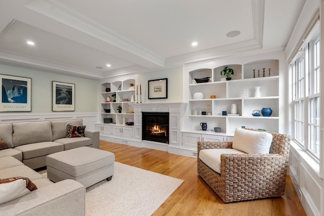 living room with light hardwood / wood-style flooring, plenty of natural light, ornamental molding, and built in features