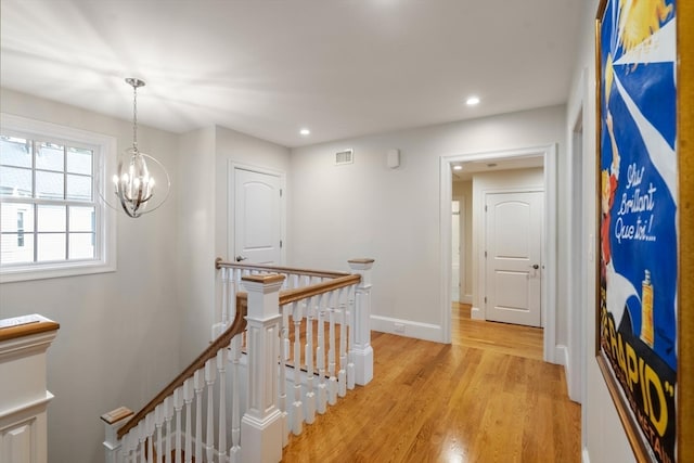 hall featuring light hardwood / wood-style flooring and an inviting chandelier