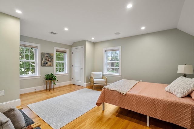 bedroom with multiple windows, light wood-type flooring, and vaulted ceiling