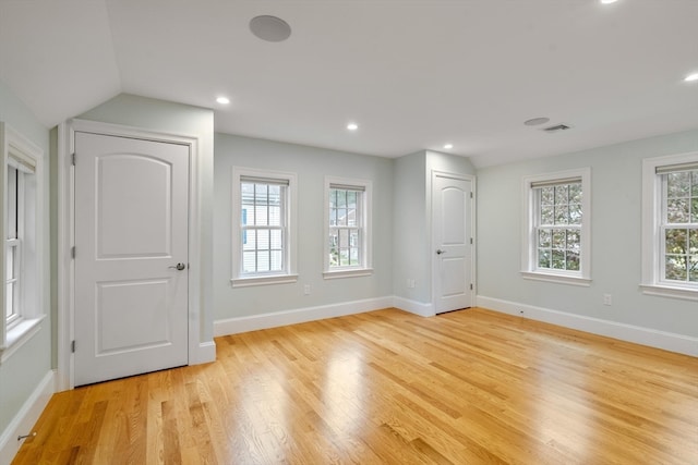 spare room with light wood-type flooring and vaulted ceiling