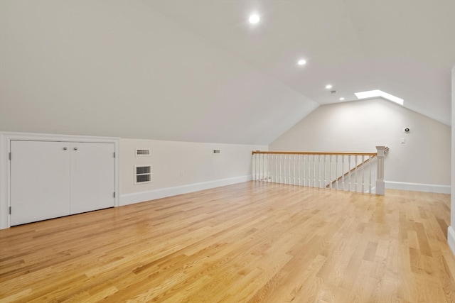 bonus room with light hardwood / wood-style flooring and lofted ceiling with skylight