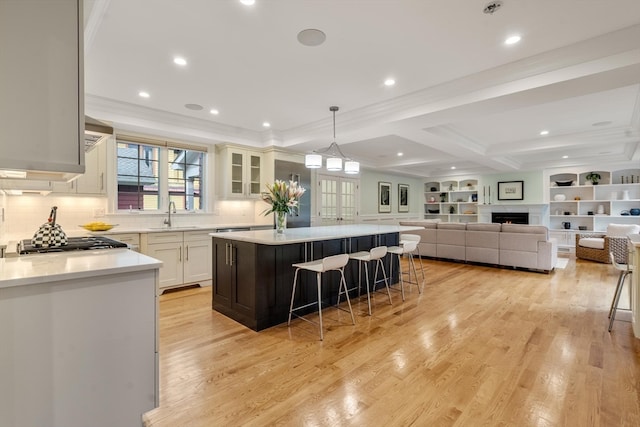 kitchen with white cabinetry, light wood-type flooring, a kitchen bar, a center island, and decorative light fixtures