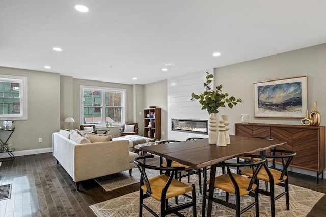 dining space with a large fireplace, baseboards, dark wood-style floors, and recessed lighting