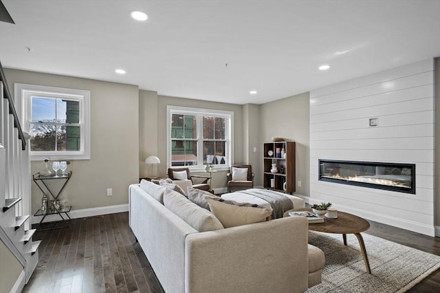 living room with dark wood-style flooring, recessed lighting, a large fireplace, baseboards, and stairs