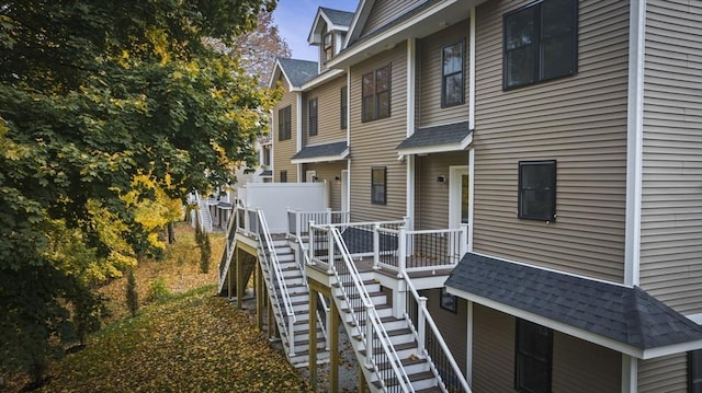 view of home's exterior with a shingled roof and stairway