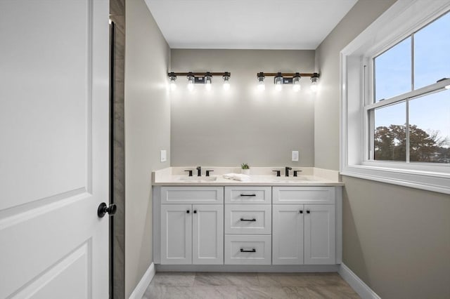 full bath with marble finish floor, baseboards, and a sink