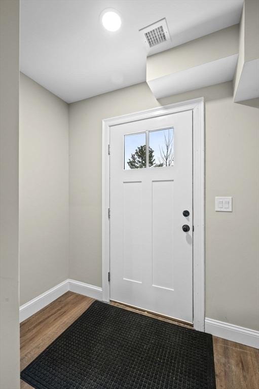 doorway featuring visible vents, baseboards, and wood finished floors