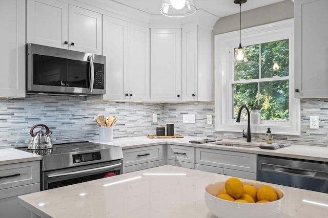 kitchen featuring light stone counters, decorative light fixtures, stainless steel appliances, backsplash, and white cabinets