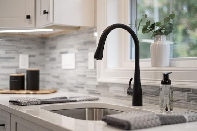 details featuring tasteful backsplash, light countertops, white cabinetry, and a sink