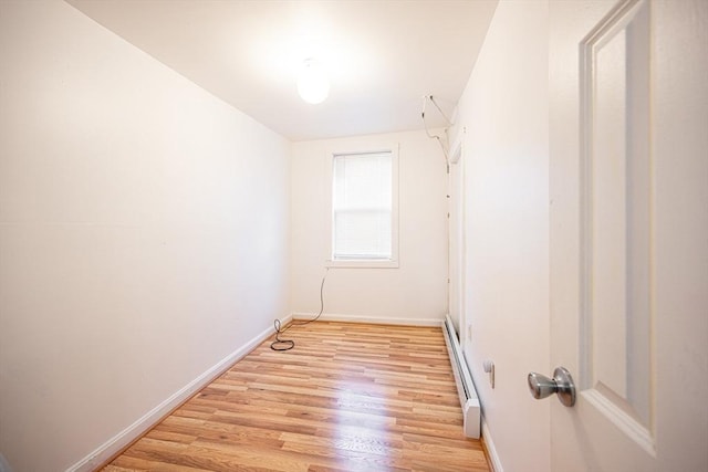 unfurnished room with light wood-type flooring and a baseboard heating unit