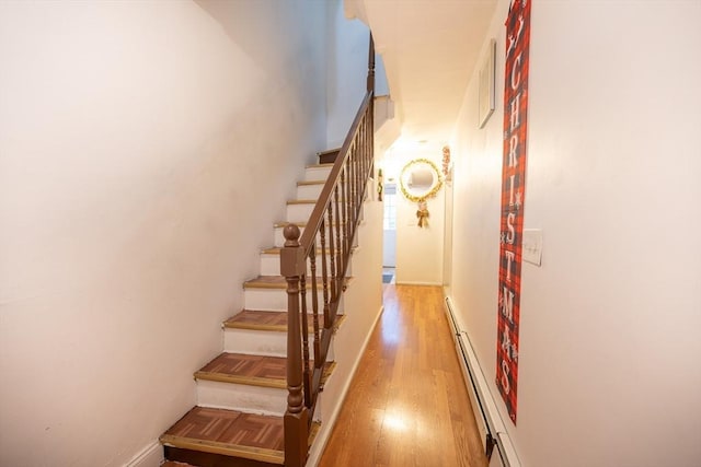 stairs with a baseboard radiator and wood-type flooring