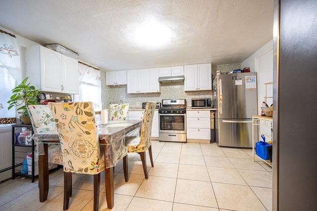 kitchen with a textured ceiling, white cabinetry, light tile patterned floors, and appliances with stainless steel finishes