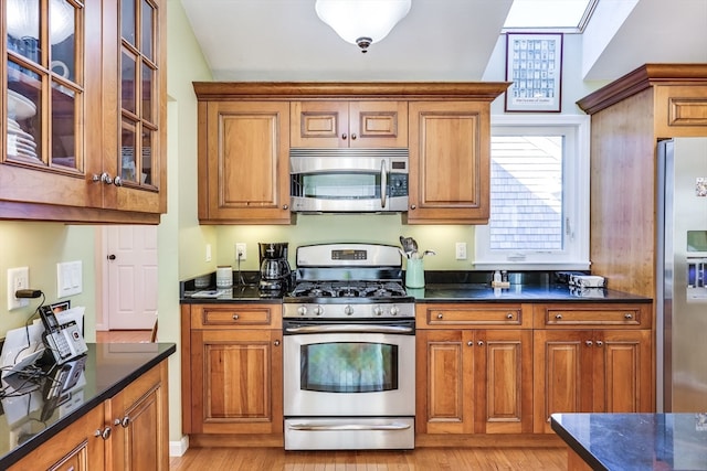 kitchen with dark stone counters, light wood-type flooring, lofted ceiling, and stainless steel appliances