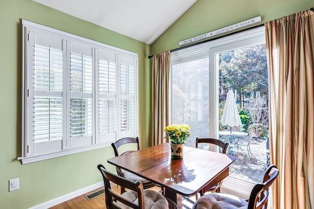 dining area with wood-type flooring and vaulted ceiling