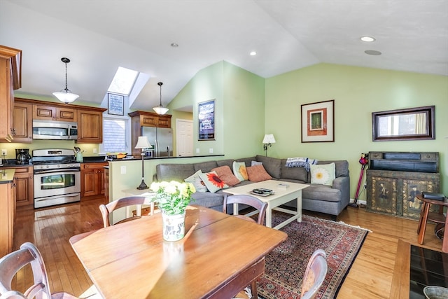 dining area with lofted ceiling with skylight and wood-type flooring