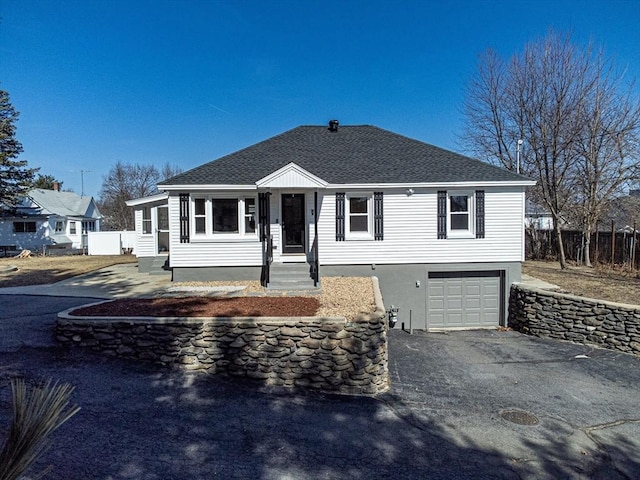 ranch-style house with aphalt driveway, roof with shingles, an attached garage, and fence