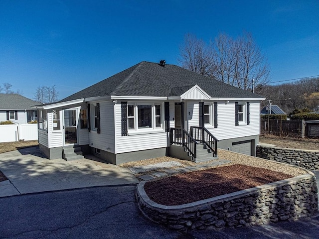 view of front of house with roof with shingles, a garage, and fence