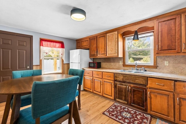 kitchen with white refrigerator, sink, a wealth of natural light, and light wood-type flooring