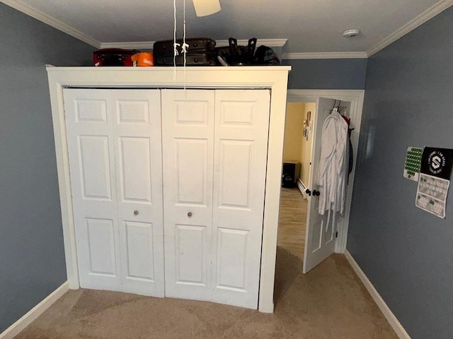 carpeted bedroom with crown molding, a closet, and baseboards