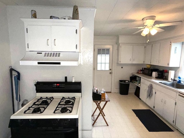 kitchen featuring a sink, exhaust hood, gas range, a ceiling fan, and white cabinets