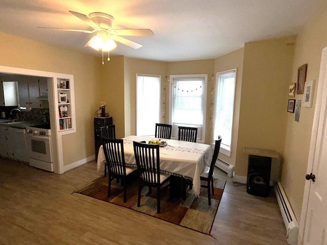 dining area with a wealth of natural light, a baseboard radiator, and wood finished floors