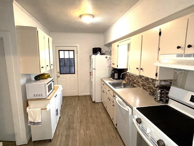 kitchen featuring a textured ceiling, under cabinet range hood, white appliances, light wood finished floors, and a sink