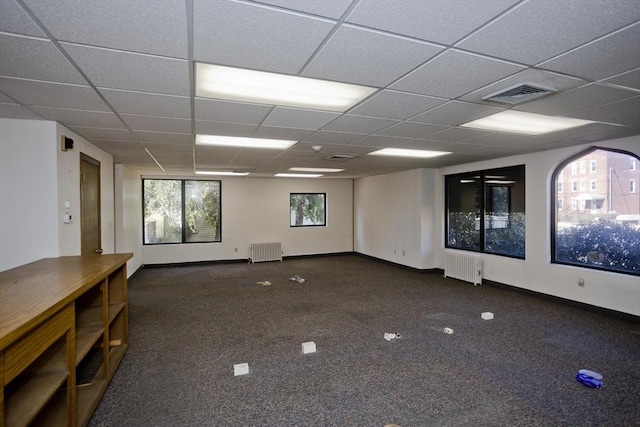 carpeted spare room with radiator, radiator heating unit, visible vents, a paneled ceiling, and baseboards